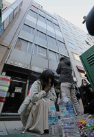 People pray on Tuesday morning for the victims of an arson attack on a clinic in a building in Osaka's Kita Ward three years ago.