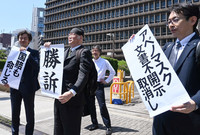 Hiroshi Kamiwaki (center), professor at Kobe Gakuin University, holds up a paper reading