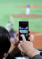 A spectator's smartphone capturing a professional baseball official game at the Mizuho PayPay Dome Fukuoka stadium Thursday